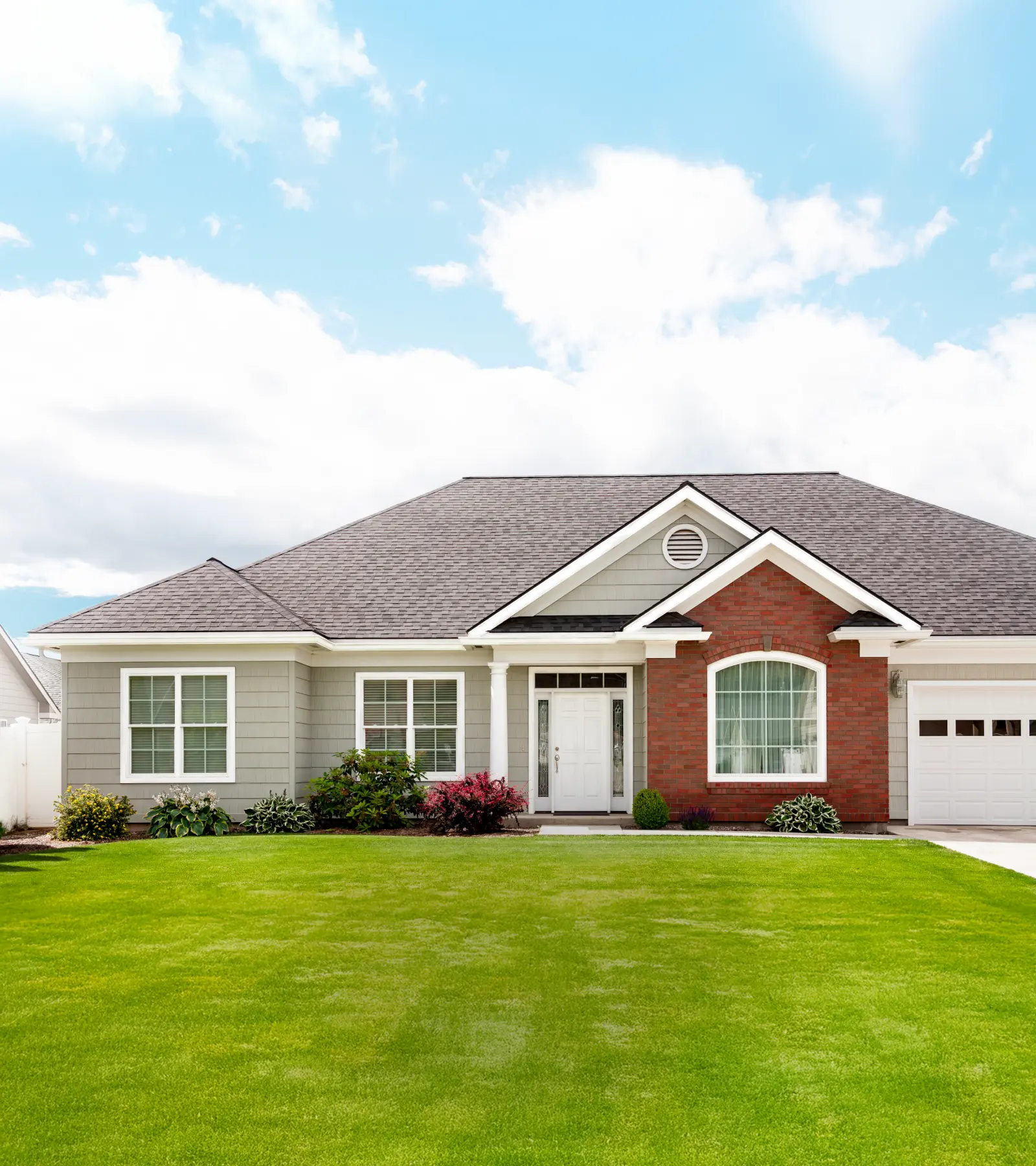 Exterior shot of a single story house with a blue sky and green grass.